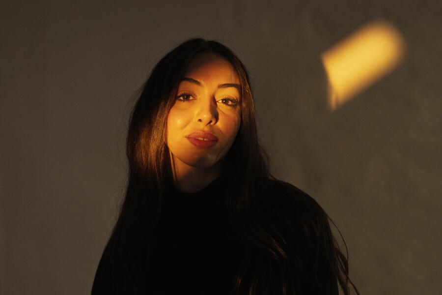 A person bathed in warm golden afternoon light, eyes open, calm — softly hopeful.