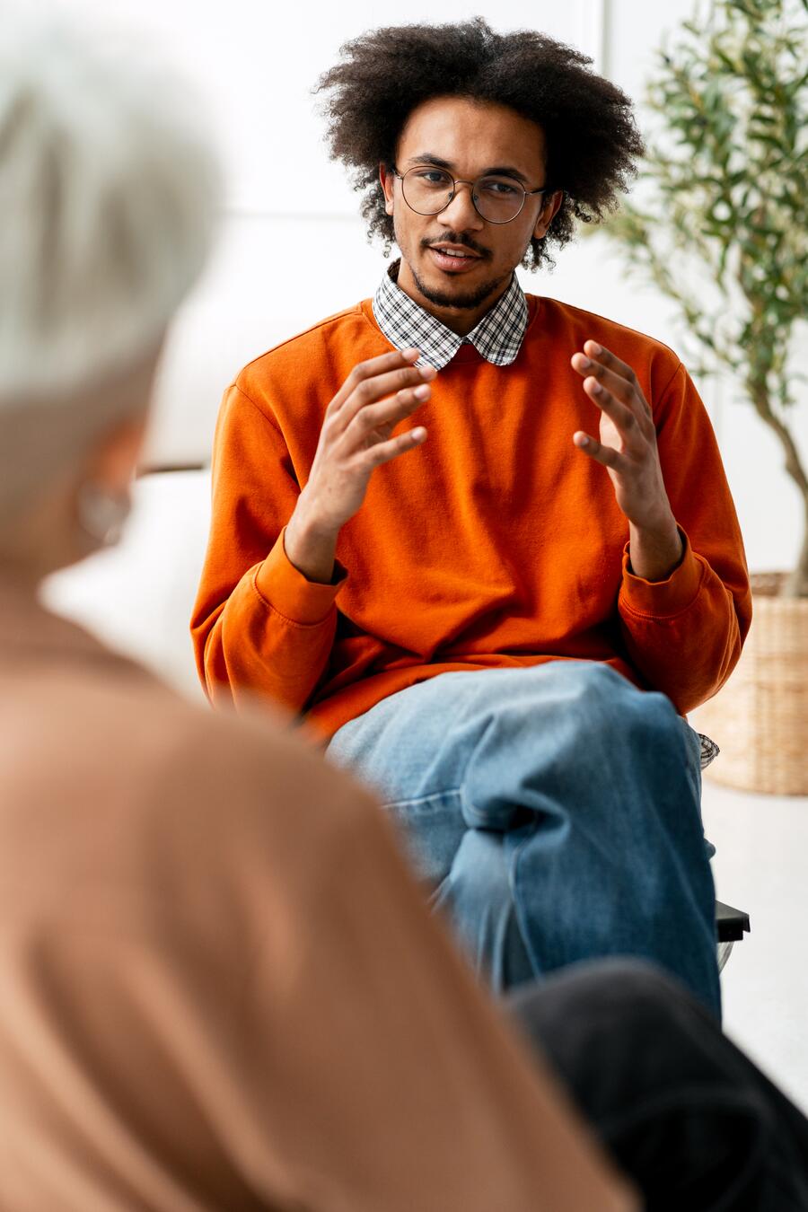 A therapist sitting across from a client in a softly-lit office, leaning slightly forward in active engagement.