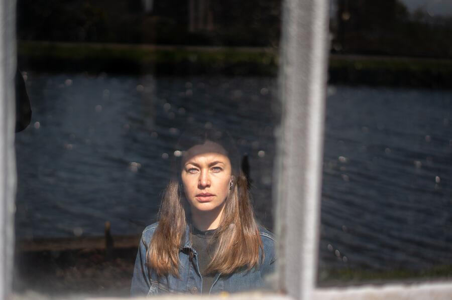 A person in soft window light, looking thoughtfully outside.